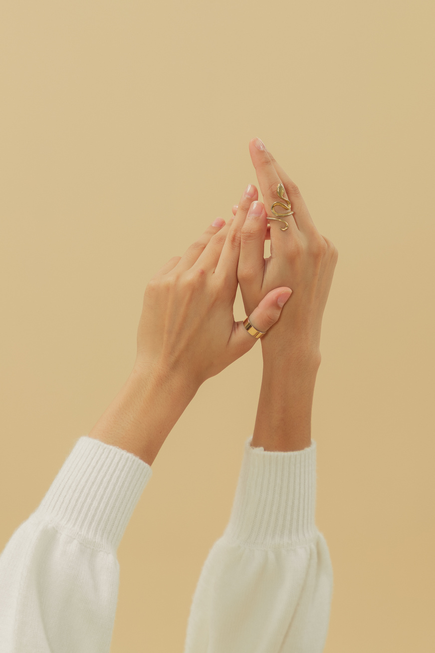 Hands with Assorted Gold Rings on Beige Background